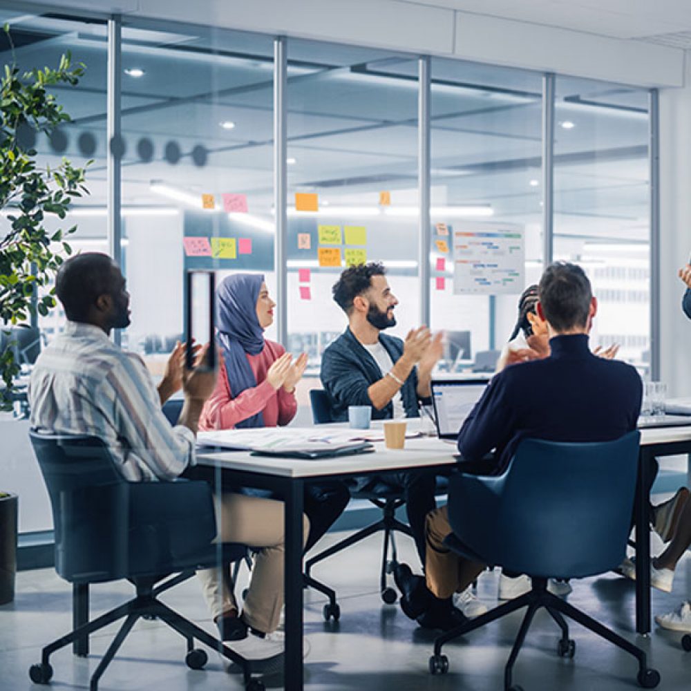 Multi-Ethnic Office Conference Room. Indian CEO does Presentation for Diverse Young Entrepreneurs, Talking, Using TV with Infographics, Statistics, Graphs. Businesspeople Invest in e-Commerce Startup